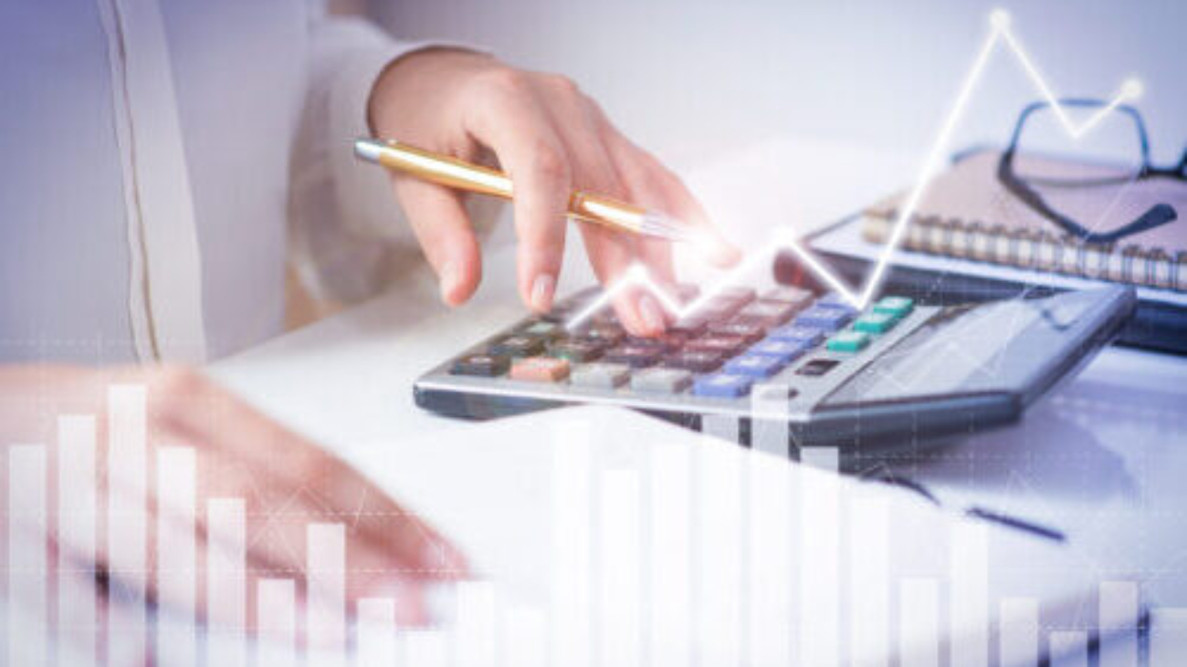 Accountant calculating profit with financial analysis graphs. Notebook, glasses and calculator lying on desk. Accountancy concept. Cropped view.