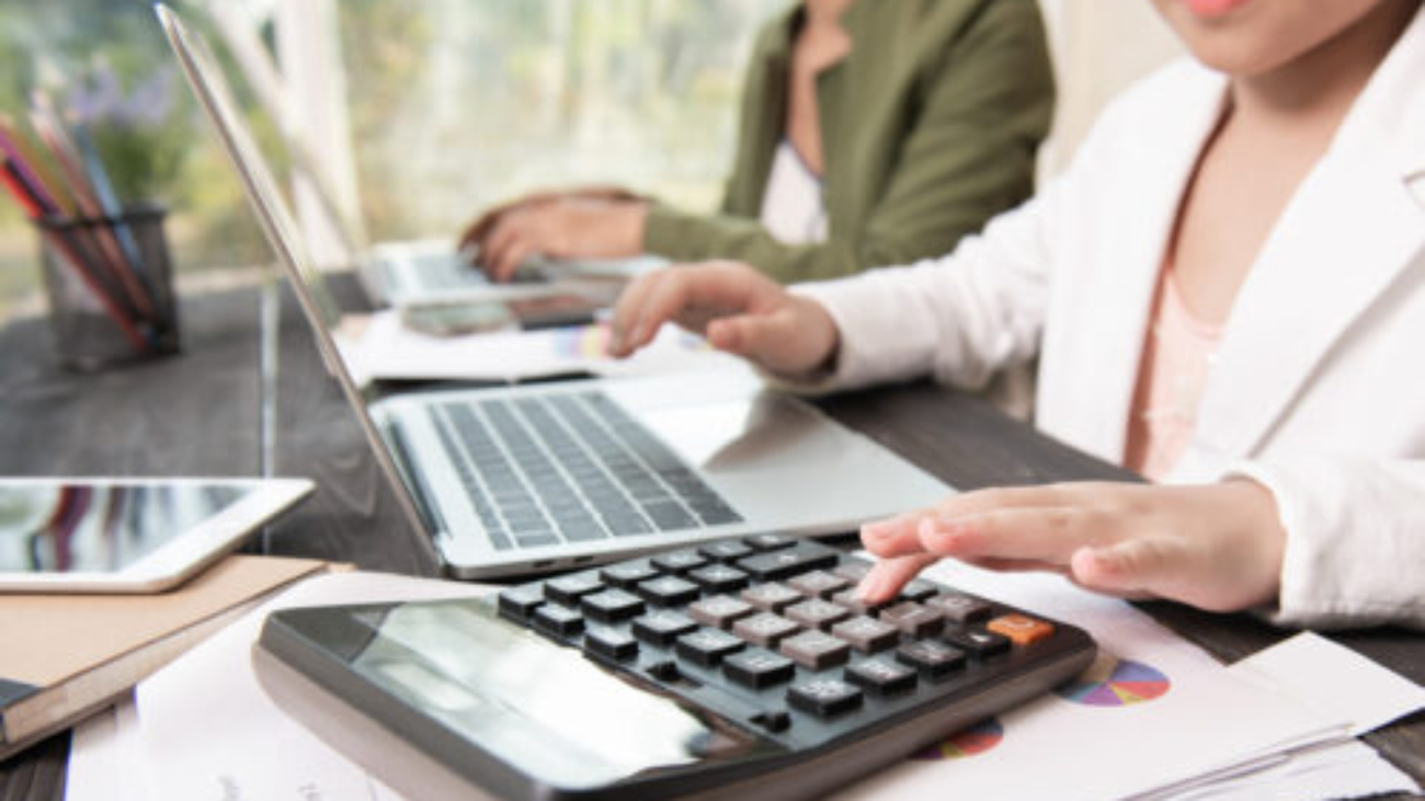 Business woman working teamwork process, Business team using a calculator to calculate the numbers of statistic business profits growth rate on documents graph data, his desk in a office.