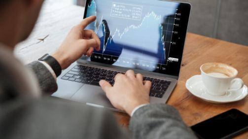 Cropped image of business man sitting by the table in cafe and analyzing indicators on laptop computer