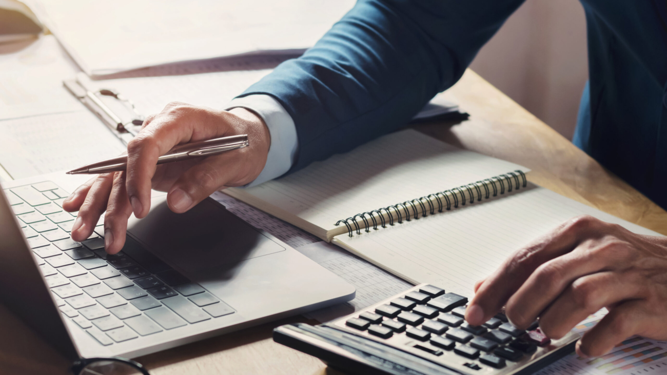 businessman workig and using calculator with laptop on desk