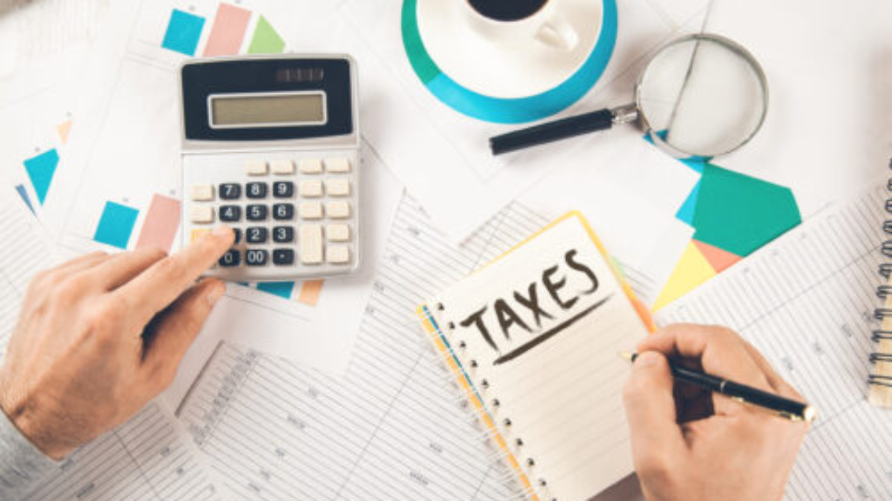 man hand taxes text on notepad with calculator on document