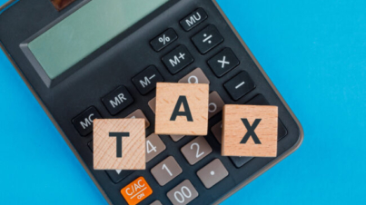 tax-planning-concept-with-wooden-cubes-calculator-blue-table-flat-lay (1)